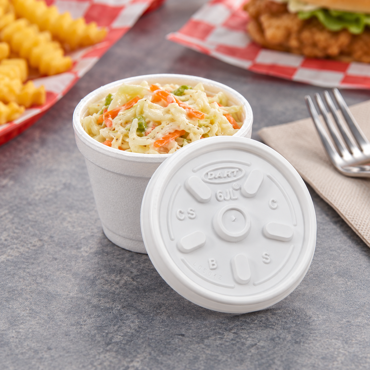 Dart 6JL lid beside a foam container of coleslaw; AI-assisted scene, food and container not included