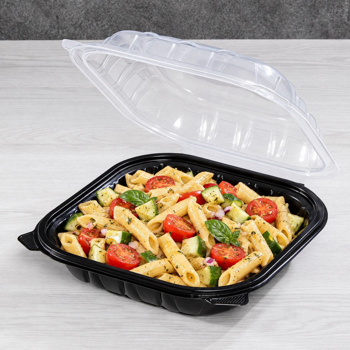 Pasta salad serving example in an open Karat 9x9 black-base clear-lid takeout container